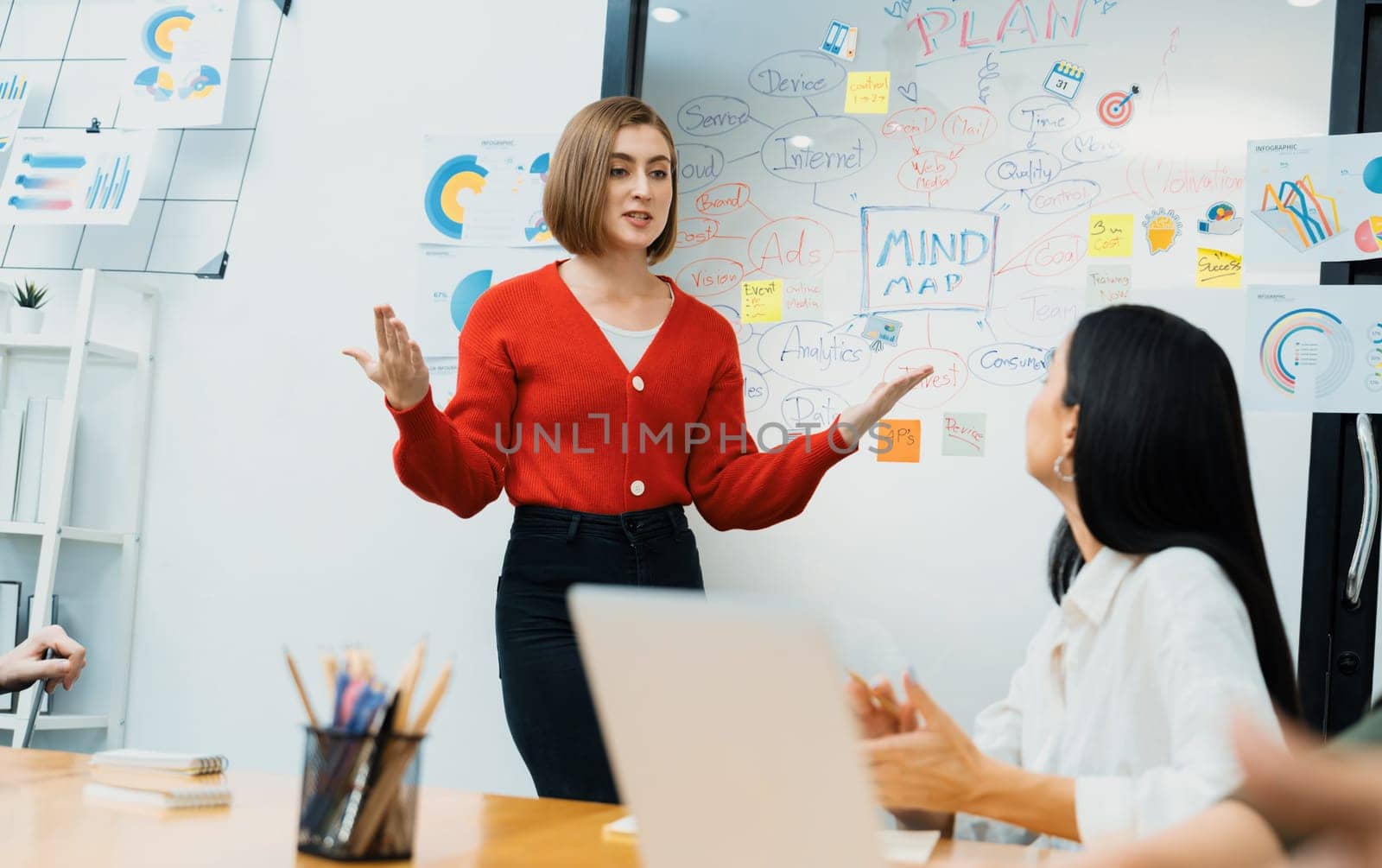 Professional attractive female leader presents creative marketing plan by using brainstorming mind mapping statistic graph and colorful sticky note at modern business meeting room. Immaculate.