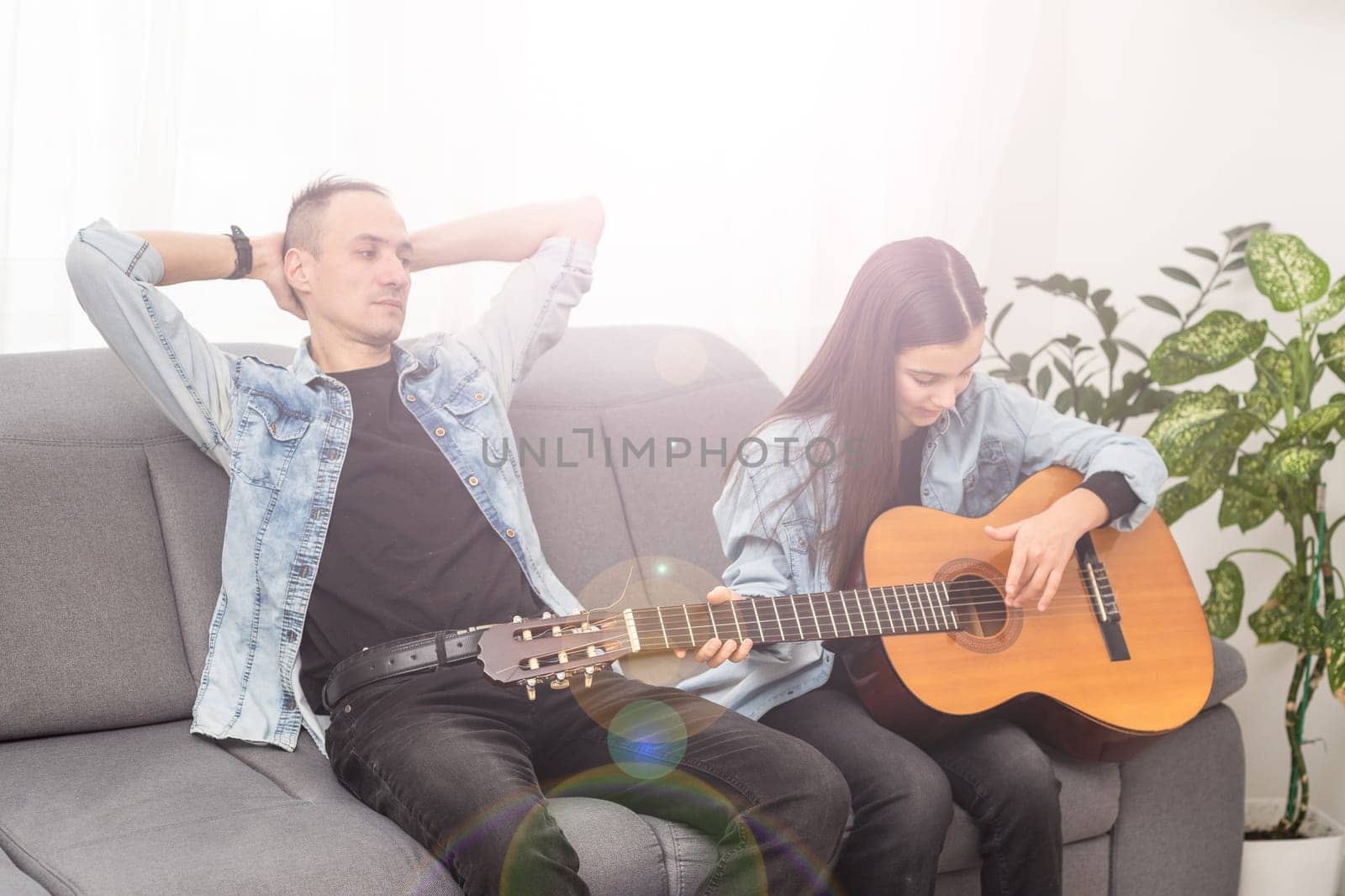 Artistic talented girl showing her latin music teacher the new song she learned to play on the acoustic guitar at home. High quality photo