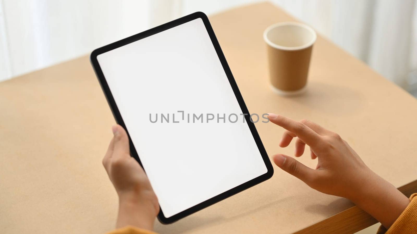 Woman hand holding digital tablet with white blank screen for advertisement. Close up view by prathanchorruangsak