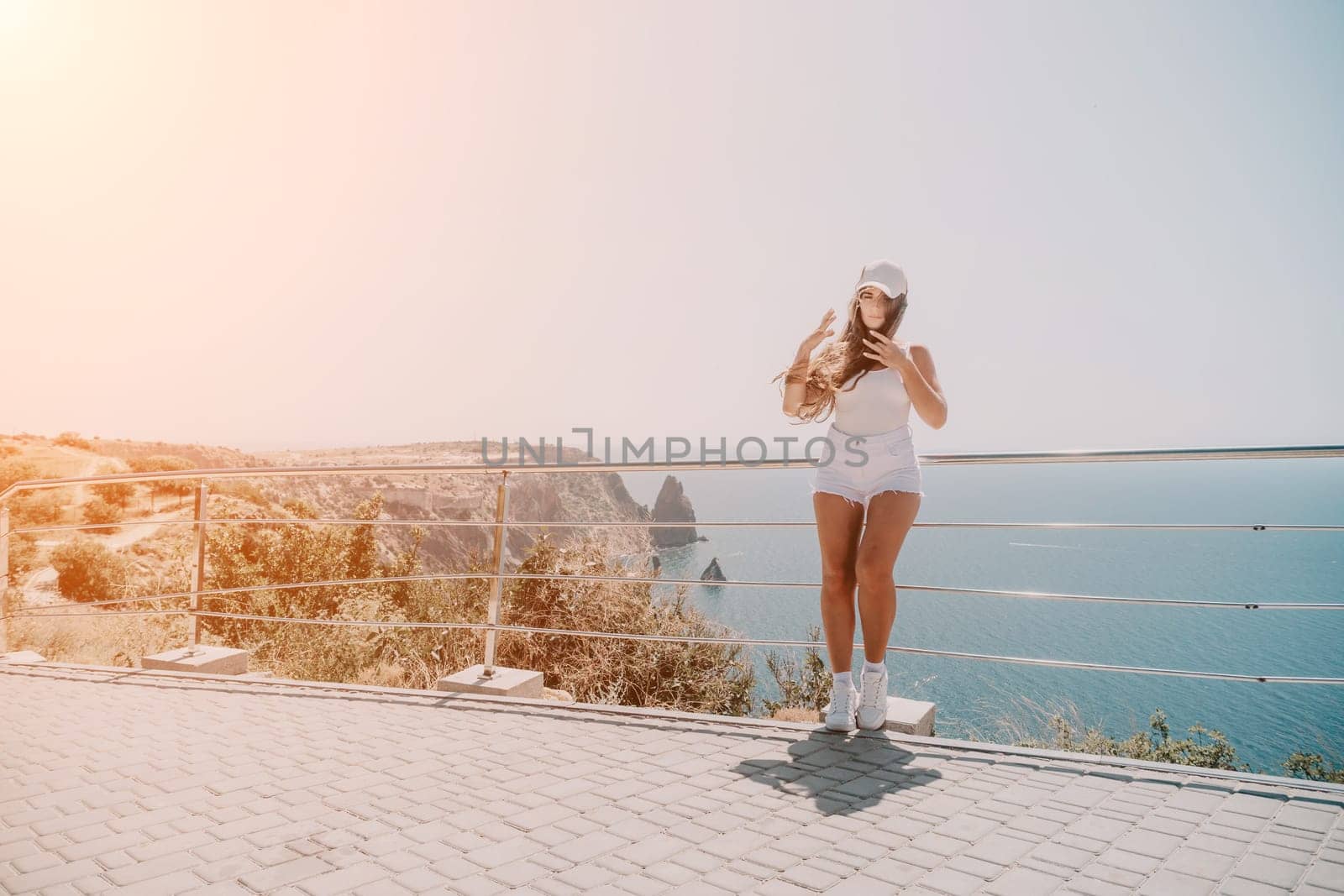 Woman summer travel sea. Happy tourist enjoy taking picture outdoors for memories. Woman traveler posing over sea bay surrounded by volcanic mountains, sharing travel adventure journey by panophotograph