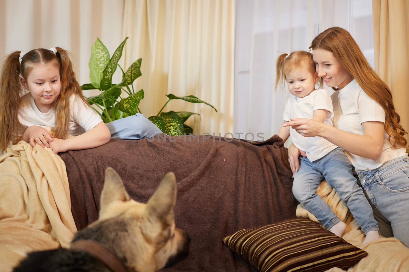 Loving family with mother, daughter sisters and big dog in living room. Woman mom, small child girl, female teenager who is afraid of a big pet by keleny