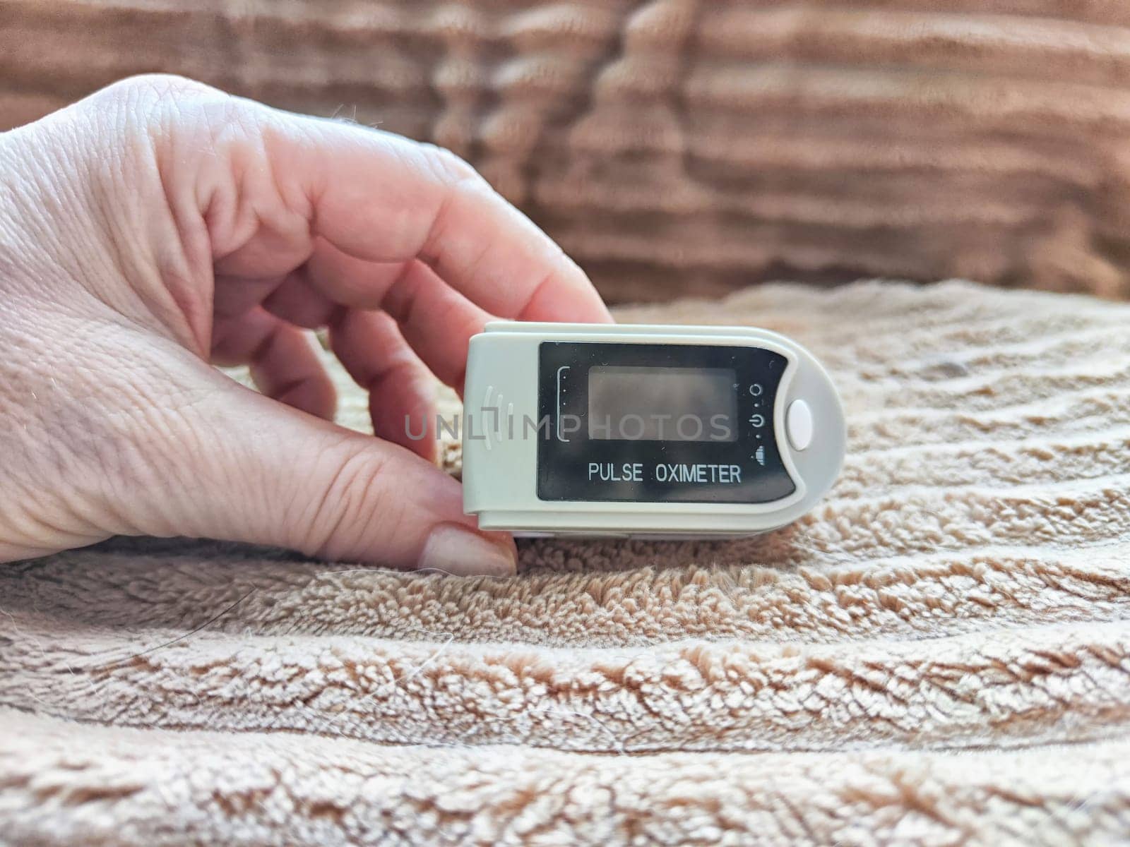 Close up of hand with a pulse oximeter on the finger.