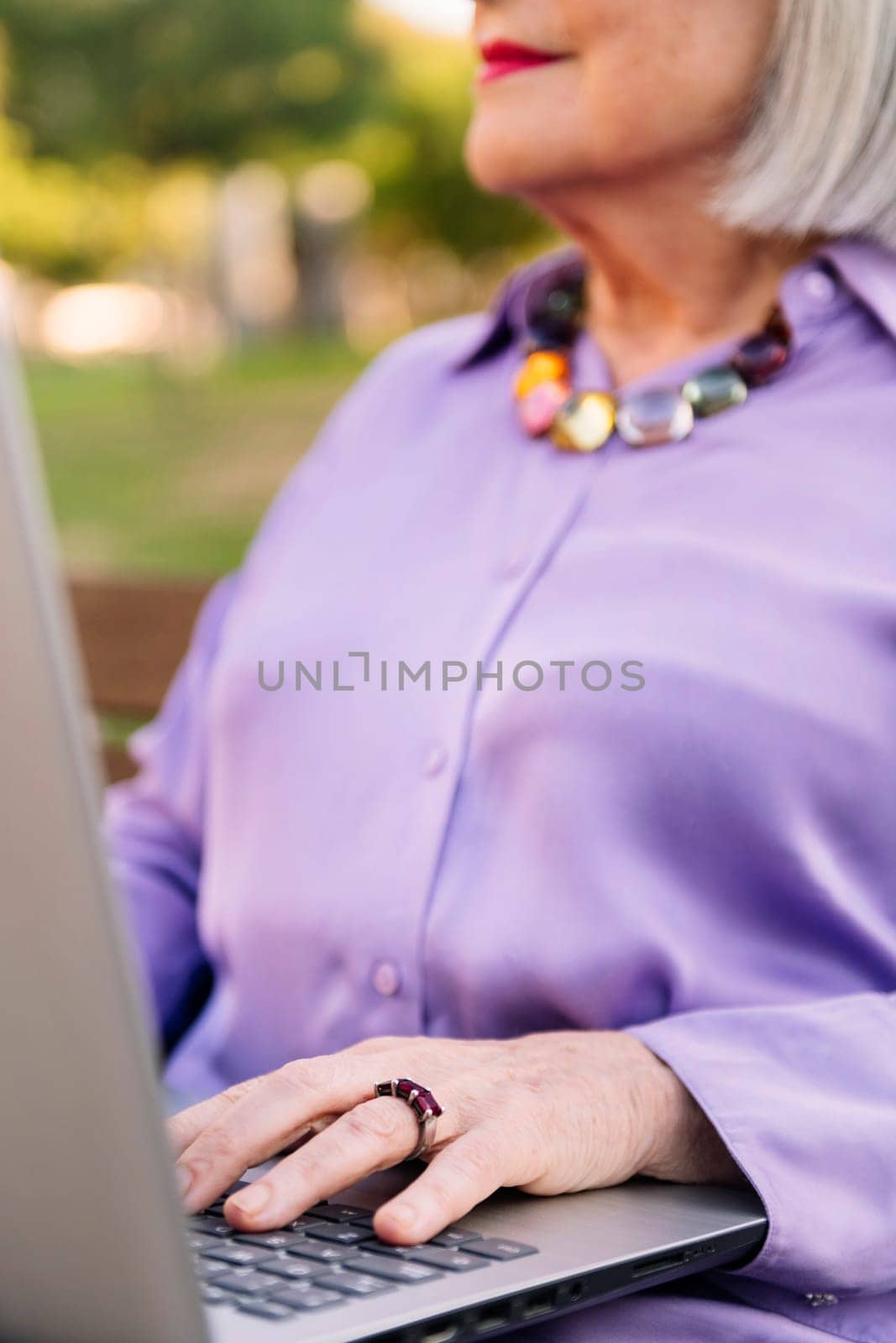 unrecognizable senior woman typing on laptop keyboard, focus on hands, concept of technology and elderly people leisure