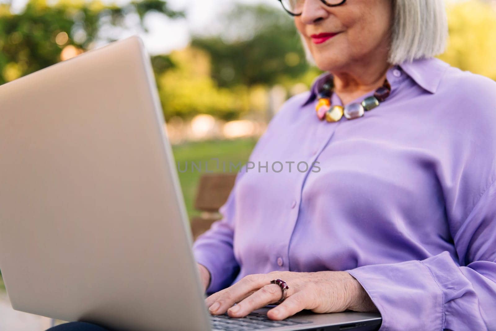 unrecognizable senior woman typing on laptop keyboard, focus on hands, concept of technology and elderly people leisure