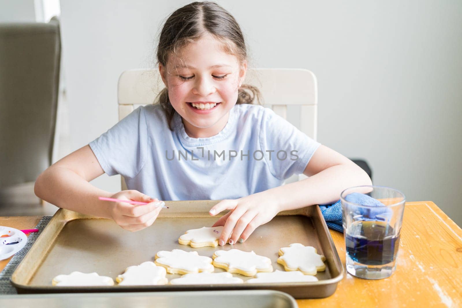 A heartwarming scene of a little girl carefully writing 'Sorry' on sugar cookies with food coloring, the cookies beautifully flooded with white royal icing.