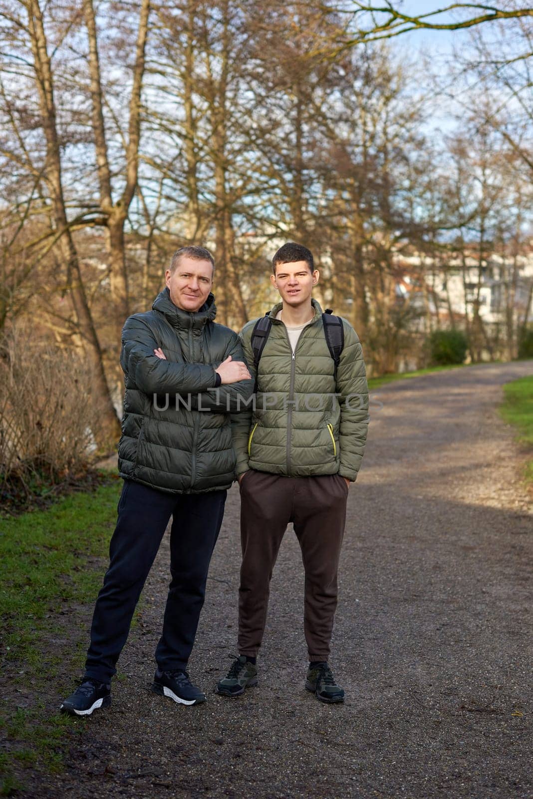 Father-Son Bond: Handsome 40-Year-Old Man and 17-Year-Old Son Standing Together in Winter or Autumn Park. by Andrii_Ko