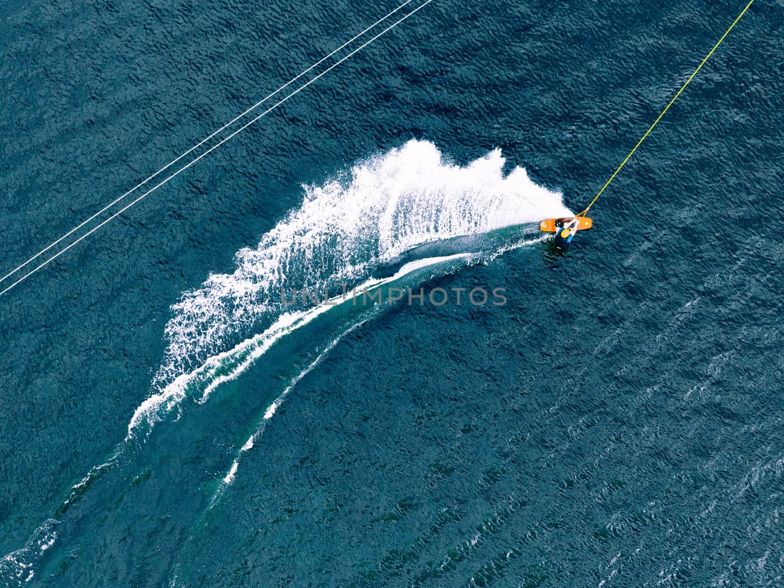 Aerial wakeboarding. Top view of awakeboard rider in wake cable park. Water sport background. Drone top down shot