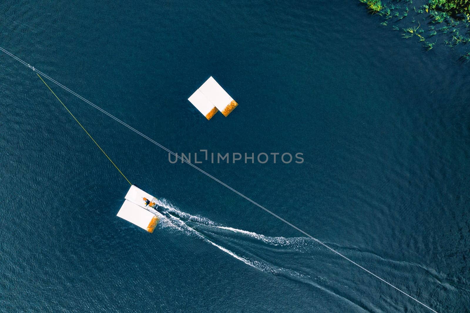 Aerial wakeboarding. Top view of awakeboard rider in wake cable park. Water sport background. Drone top down shot