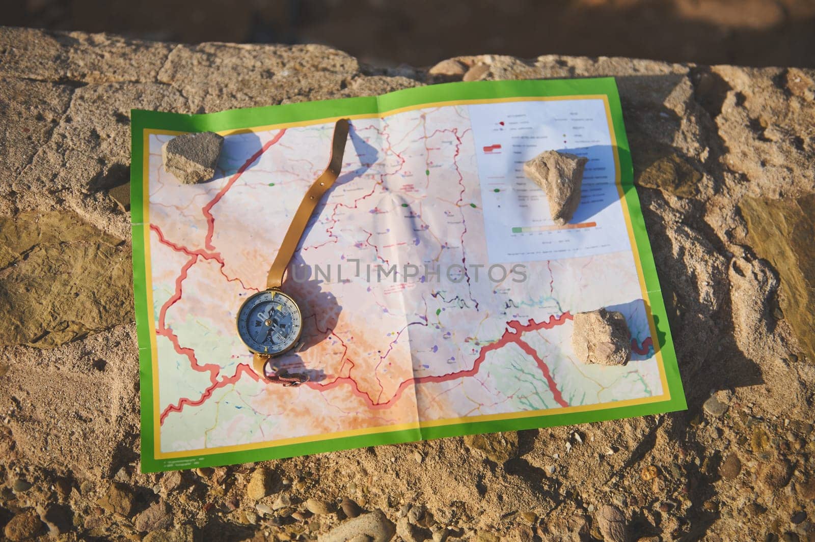 Still life. View from above of a compass lying on a map on the cliff, orienteering on the ground, a magnetic arrow points north, navigation in the seacoast. Navigational equipment. Tourism concept
