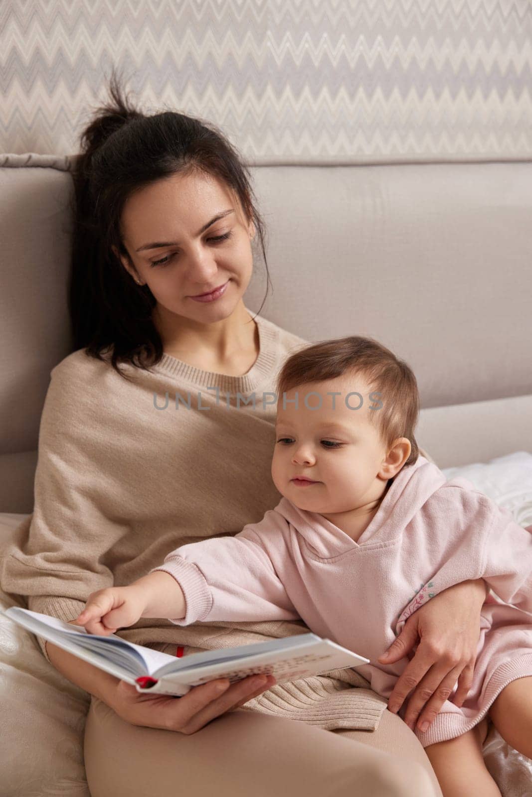 beautiful mother reading book to her child daughter on bed
