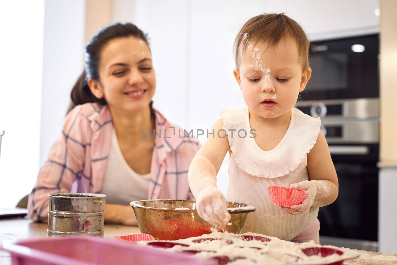 happy mother and little baby girl preparing the dough in the kitchen, child cooking cookies.