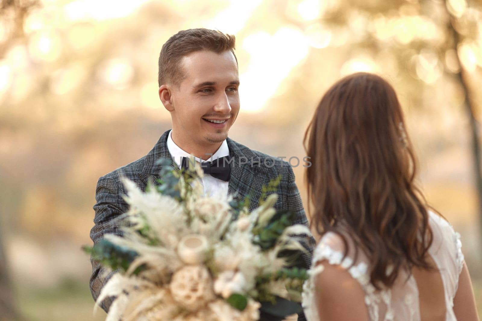 portrait of bride in white wedding dress and groom looking at each other outdoor on natural background