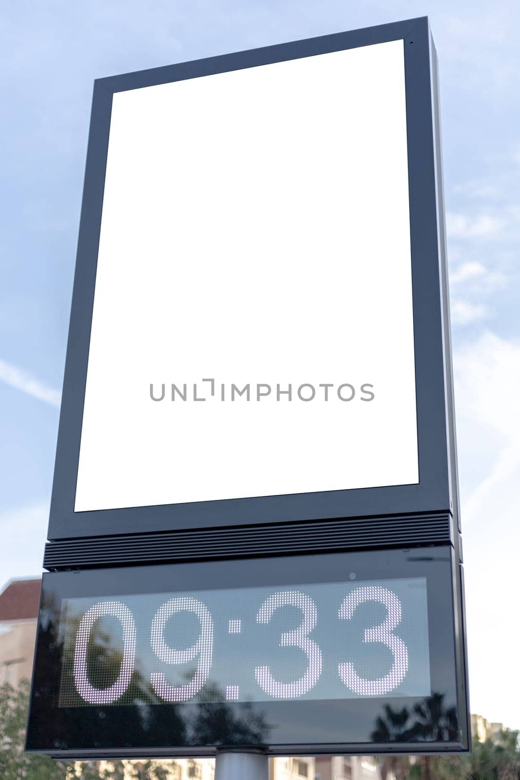 Urban digital clock post with a blank advertising panel against a cityscape, ideal for promotions. Vertical billboard mockup, empty display. Copy space for text, picture