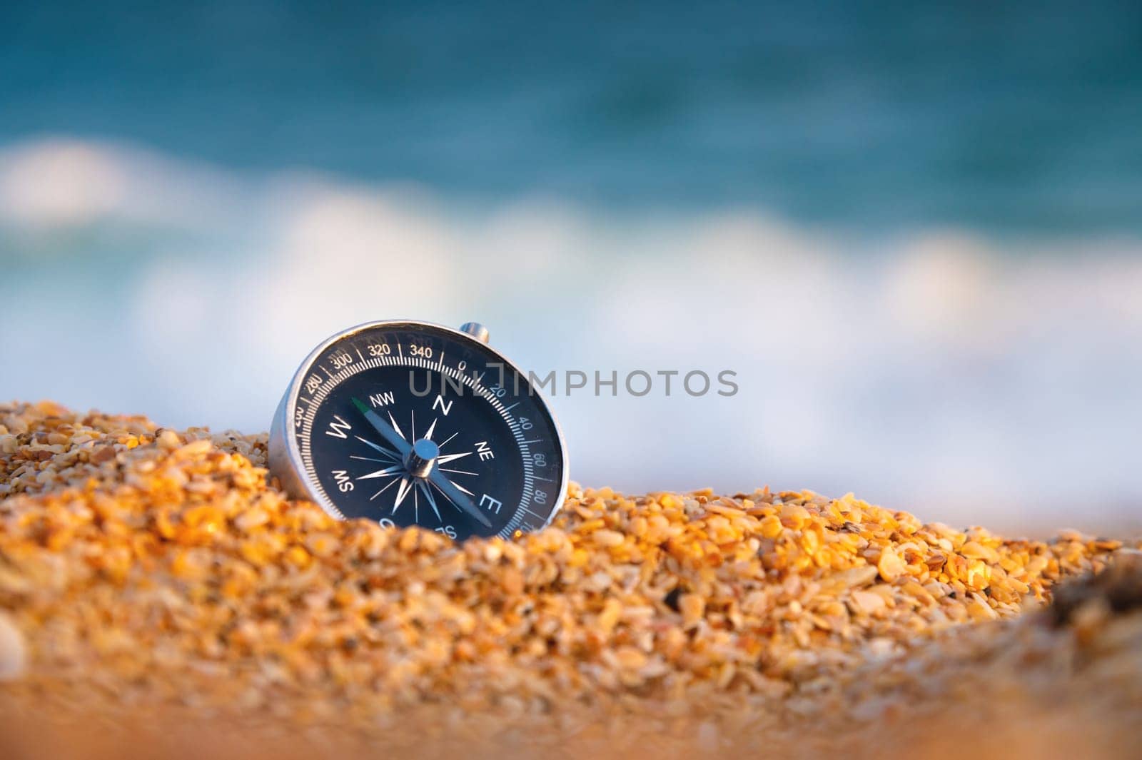 compass on sea sand and place for text. close up of navigation device on sandy beach without people, top view by yanik88