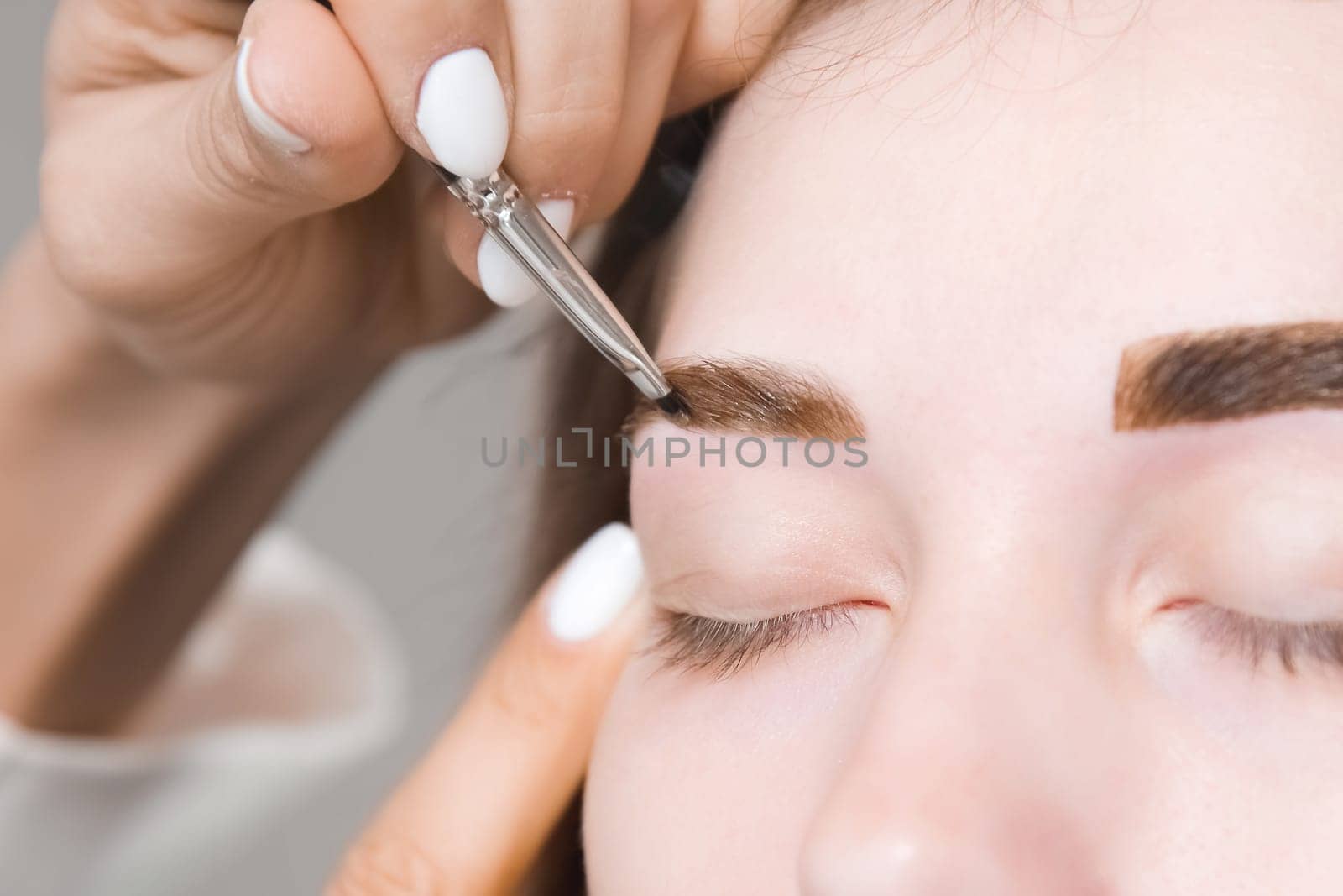 Eyebrow tinting. Close-up of a master applying eyebrow dye with a brush. Cosmetic procedures, permanent eyebrow makeup. correction and modeling of eyebrows in a beauty salon. perfect eyebrows.