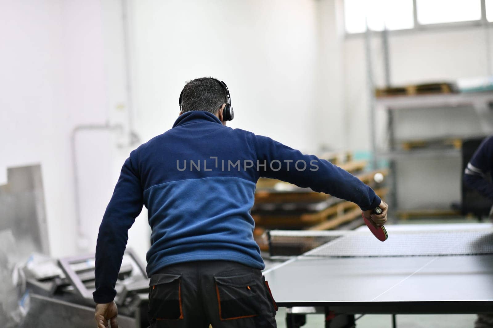 group of industry workers playing ping pong or table tennis game and relaxing in their free time at modern creative metal industry production factory