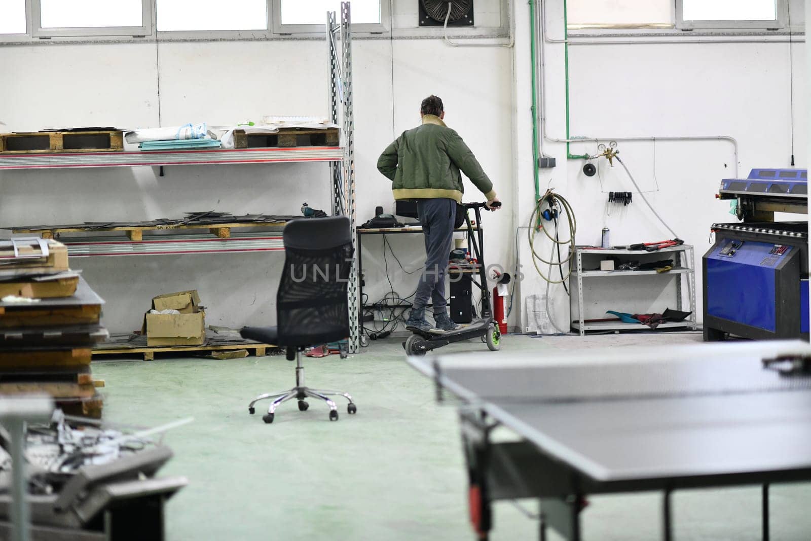 engineer in an electronic repair shop workshop rides electric scooter in a factory by dotshock