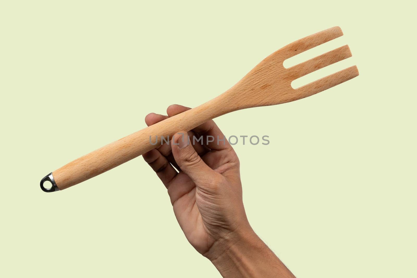 Black male hand holding a wooden cooking fork on light green background. by TropicalNinjaStudio