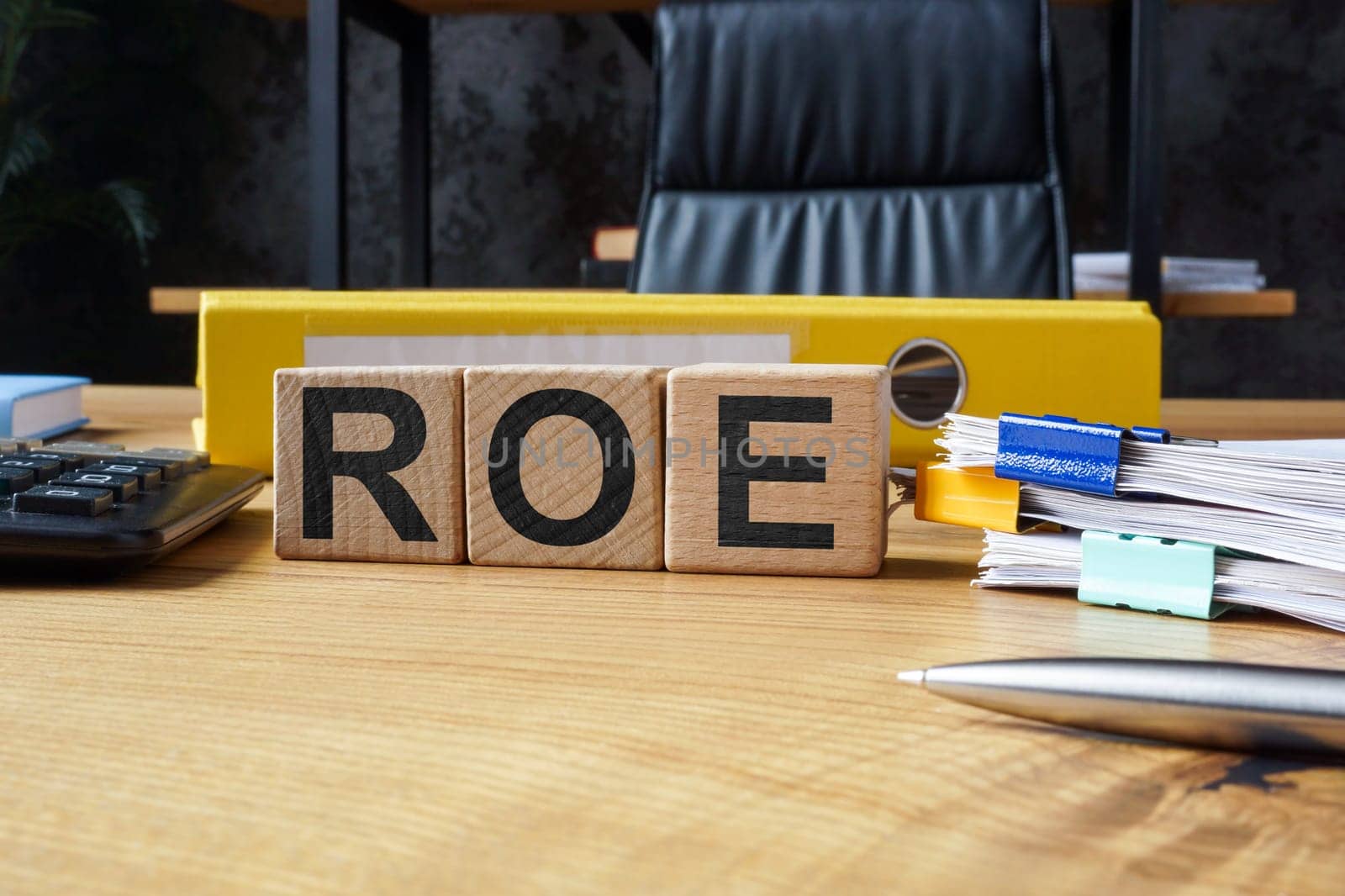 Office desk and wooden cubes with ROE Return on Equity.