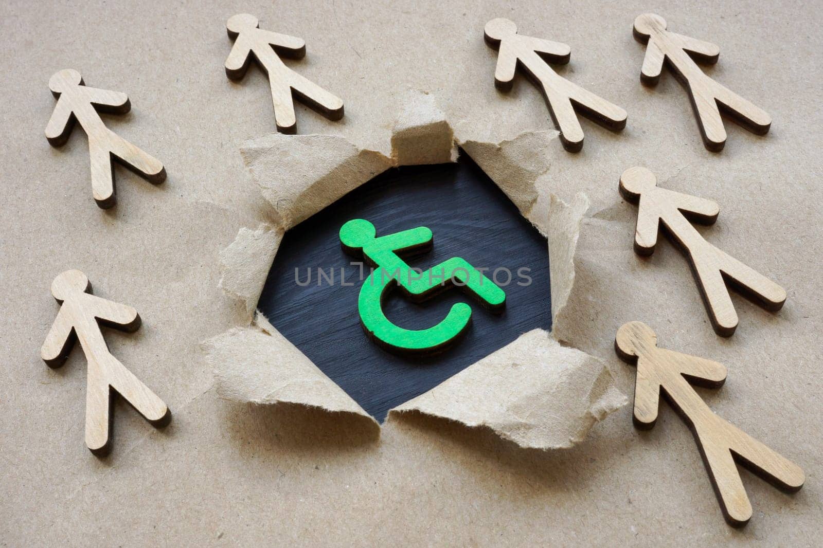 Social inclusion concept. Disabled person sign and wooden figurines.