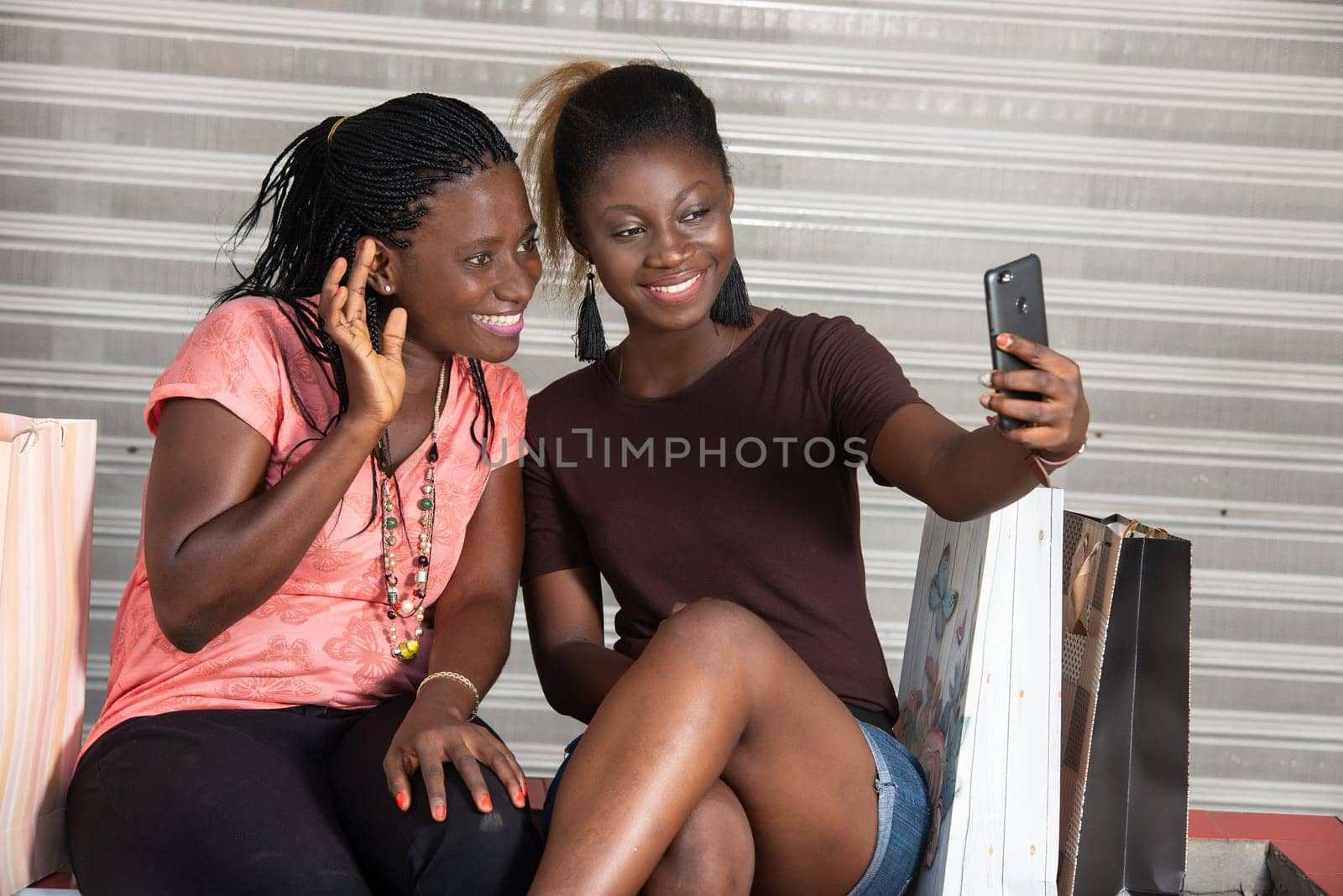 young girls sitting outside looking at mobile phone while smiling.
