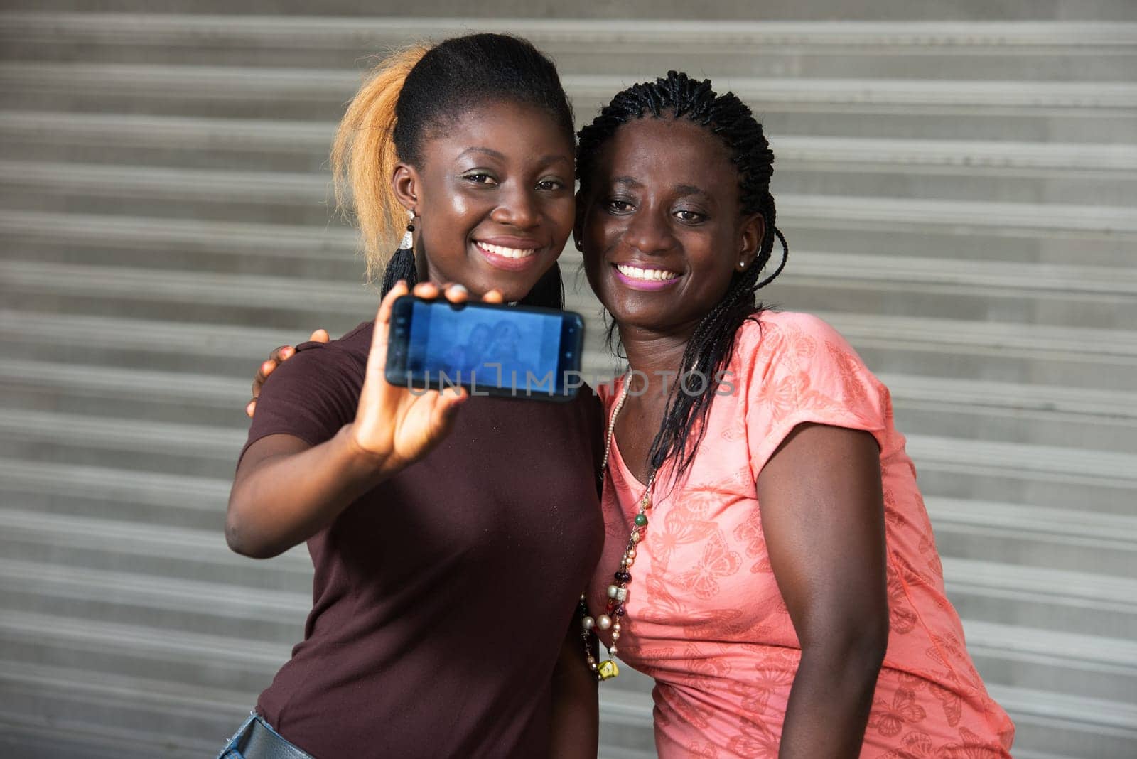 sitting girls showing the mobile phone screen smiling.