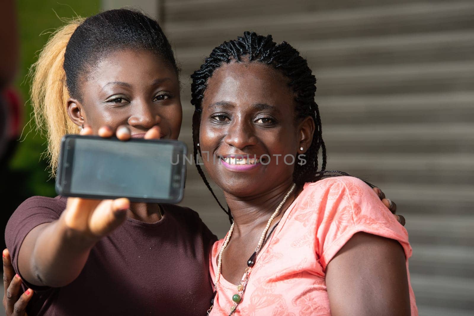sitting girls showing the mobile phone screen smiling.