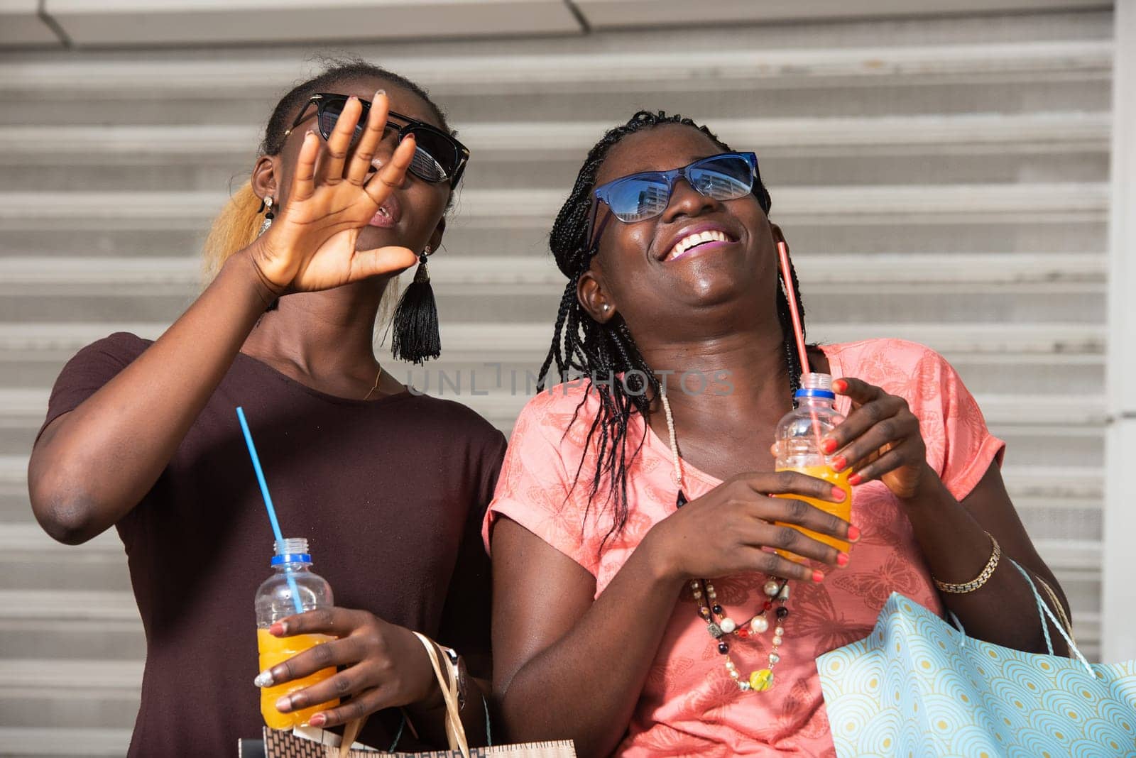 Young girls standing in glasses looking up laughing with bottles of juice in hand after shopping.
