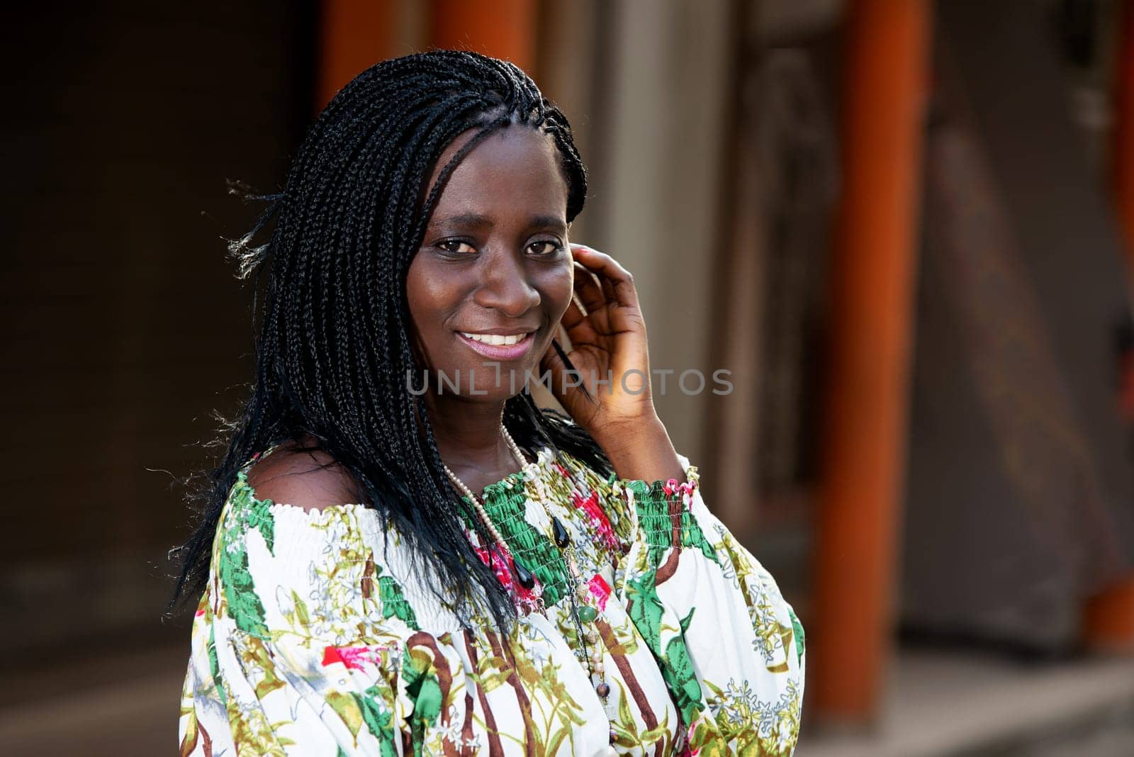 young african woman standing outdoors looking at camera smiling.