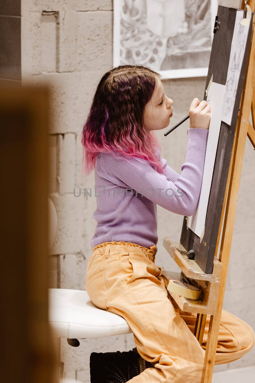 Girl 11 years old craftswoman are painting on canvas in studio standing in front of easel. Portrait of a girl painting during an art class