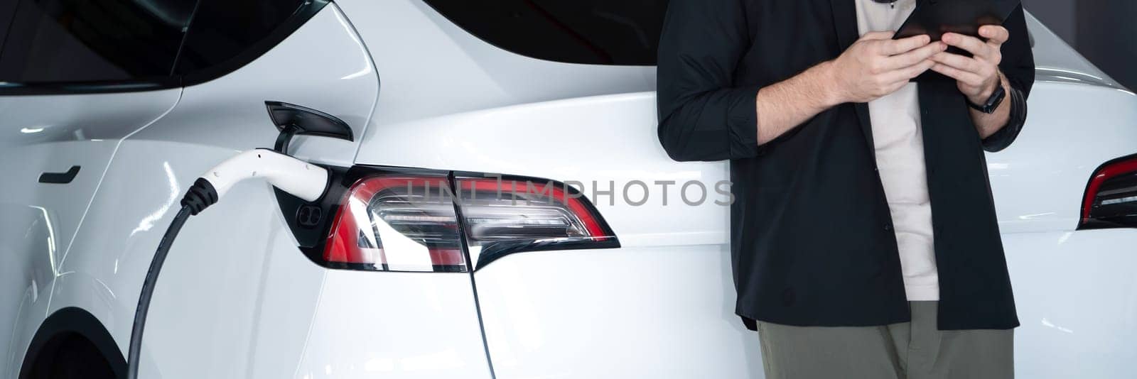 Young man travel with EV electric car to shopping center parking lot innards by biancoblue