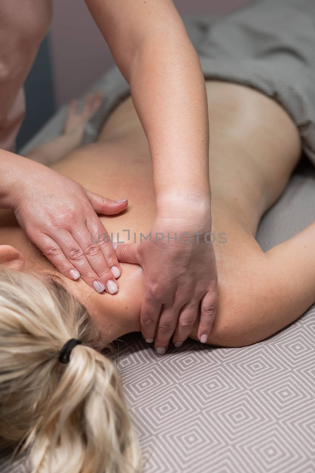 A woman undergoing a massage of the cervical-collar area. Vertical photo