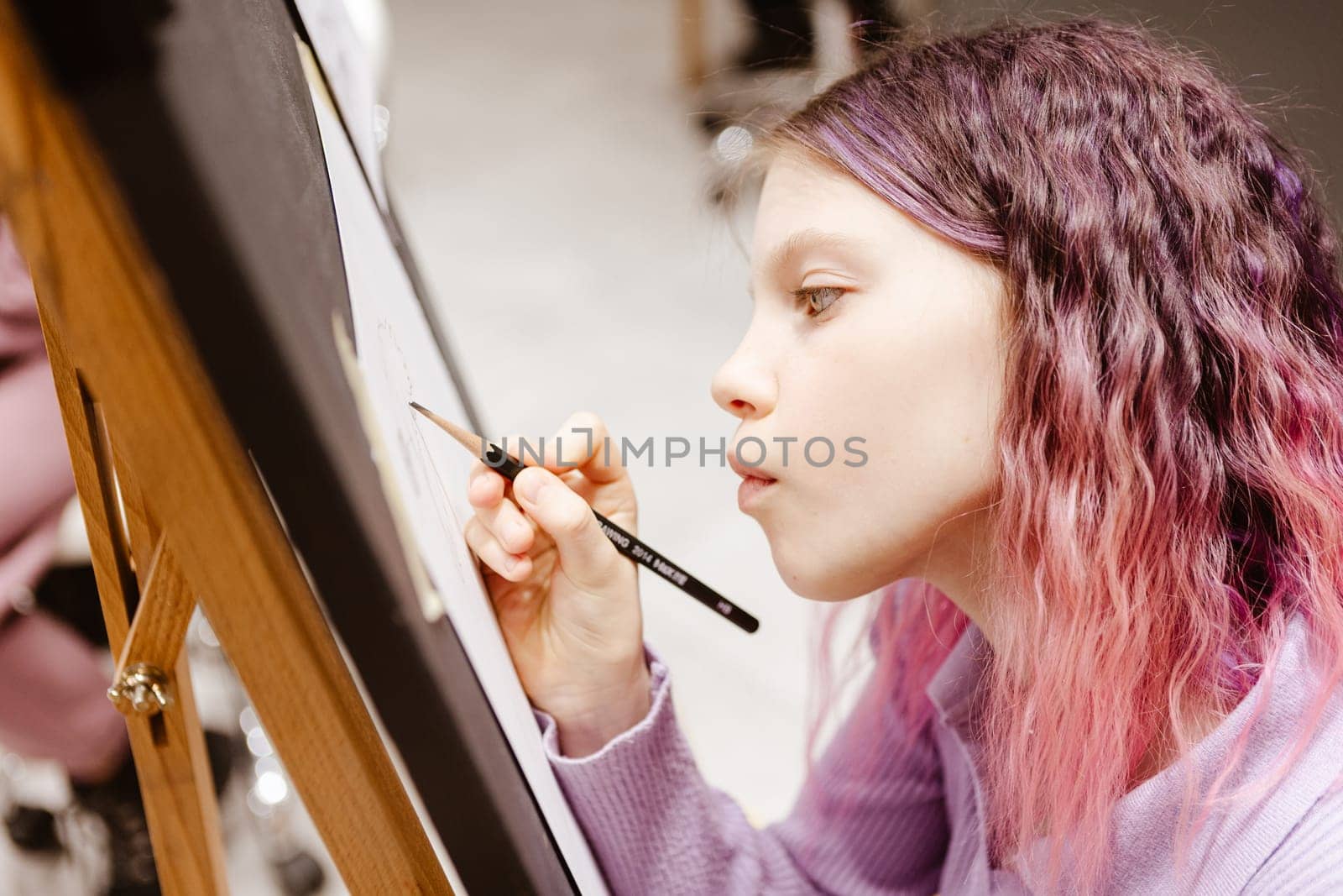 Girl 11 years old craftswoman are painting on canvas in studio standing in front of easel. Portrait of a girl painting during an art class. by sarymsakov
