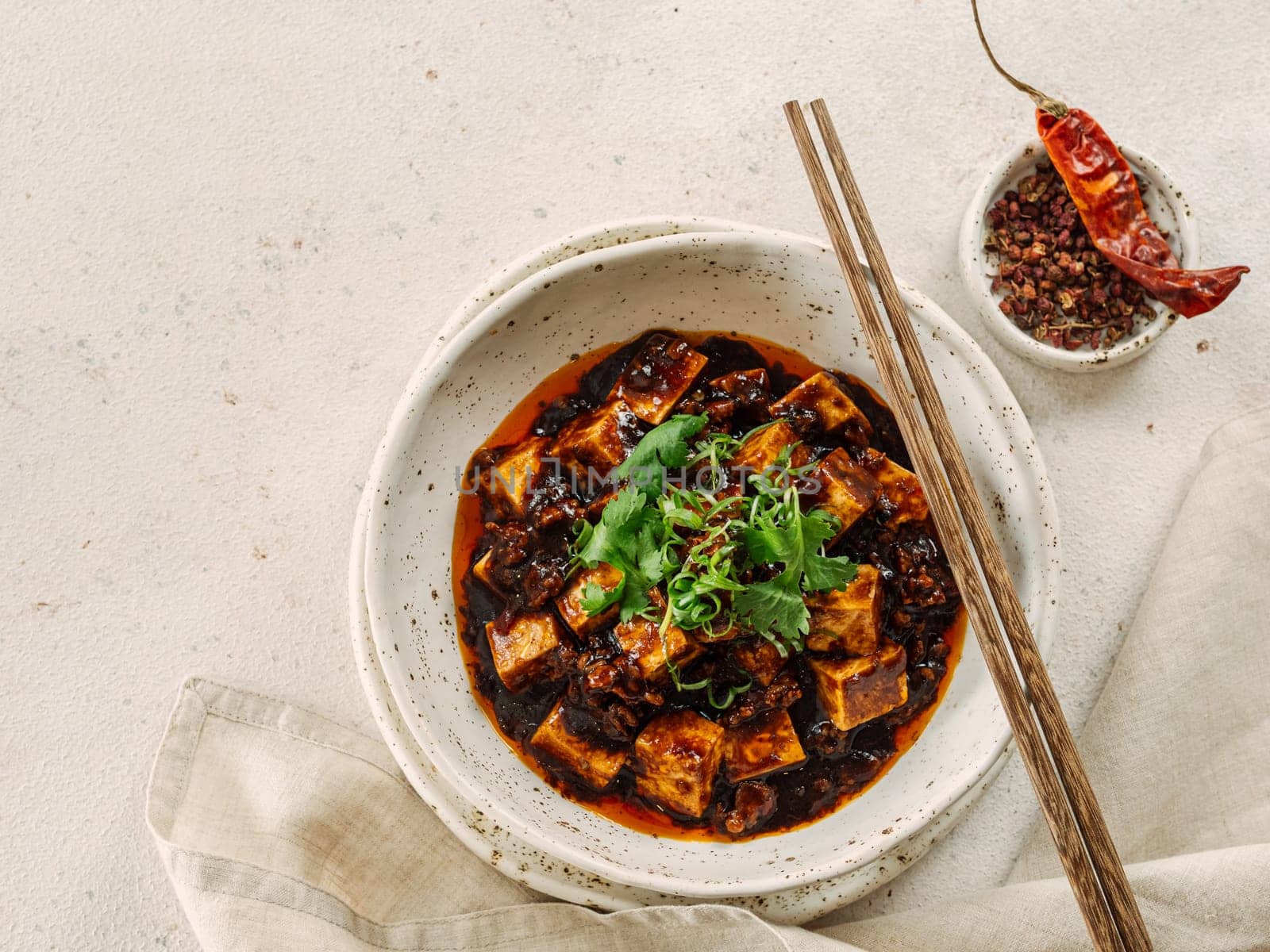 Spicy asian tofu salad or appetizer. Fried tofu decorated green onion - chinese dish with sauce. Serving Asian dish on white marble background. Top view, copy space