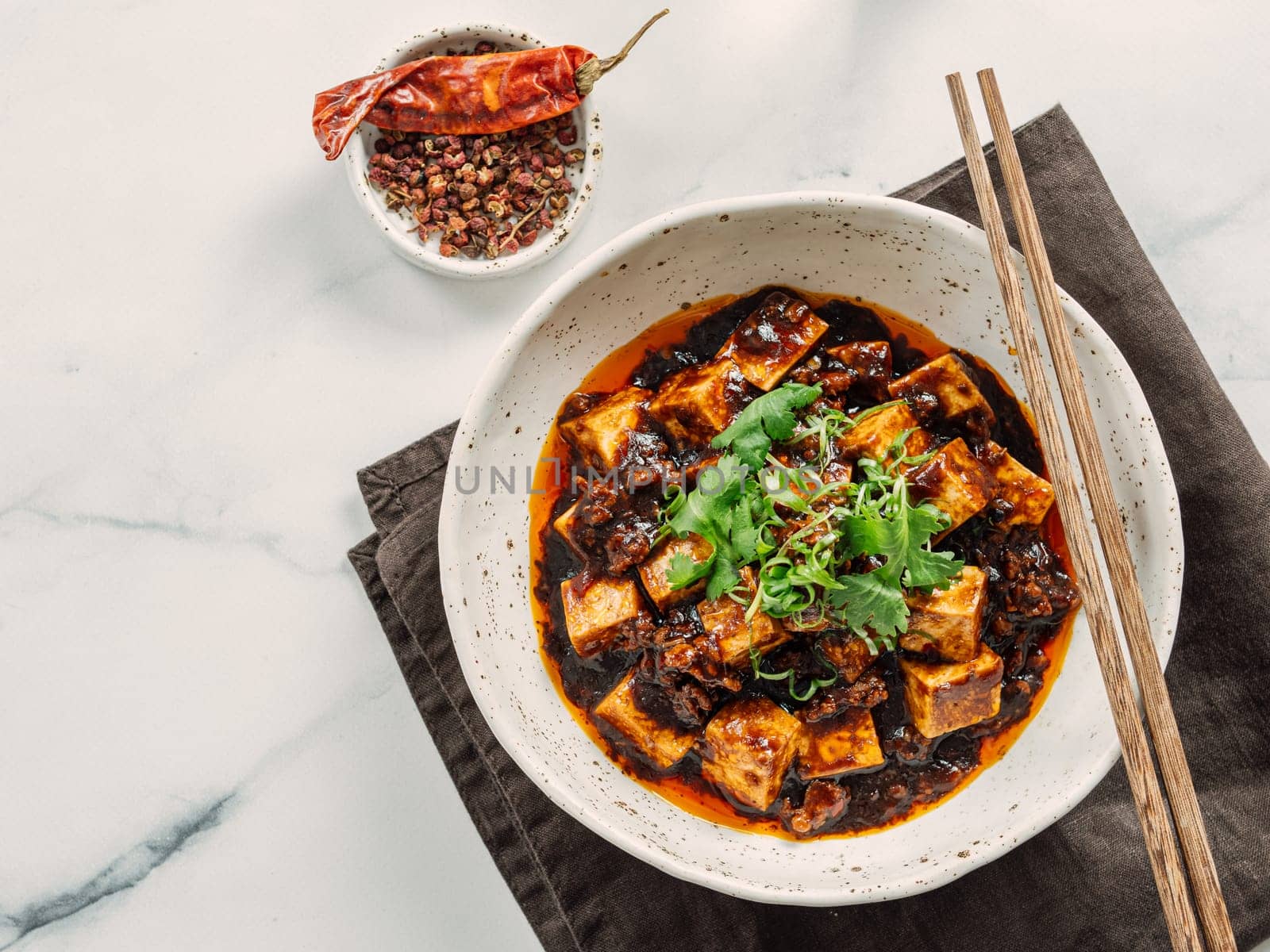 Spicy asian tofu salad or appetizer. Fried tofu decorated green onion - chinese dish with sauce. Serving Asian dish on white marble background. Top view, copy space