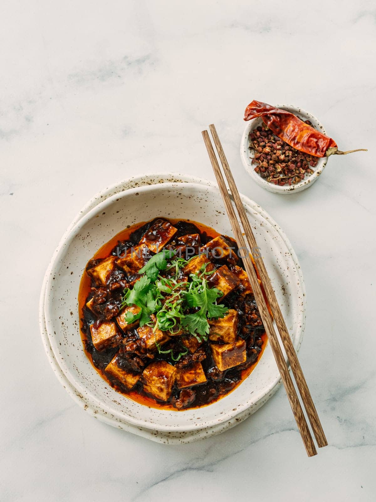 Spicy asian tofu salad or appetizer. Fried tofu decorated green onion - chinese dish with sauce. Serving Asian dish on white marble background. Top view, copy space