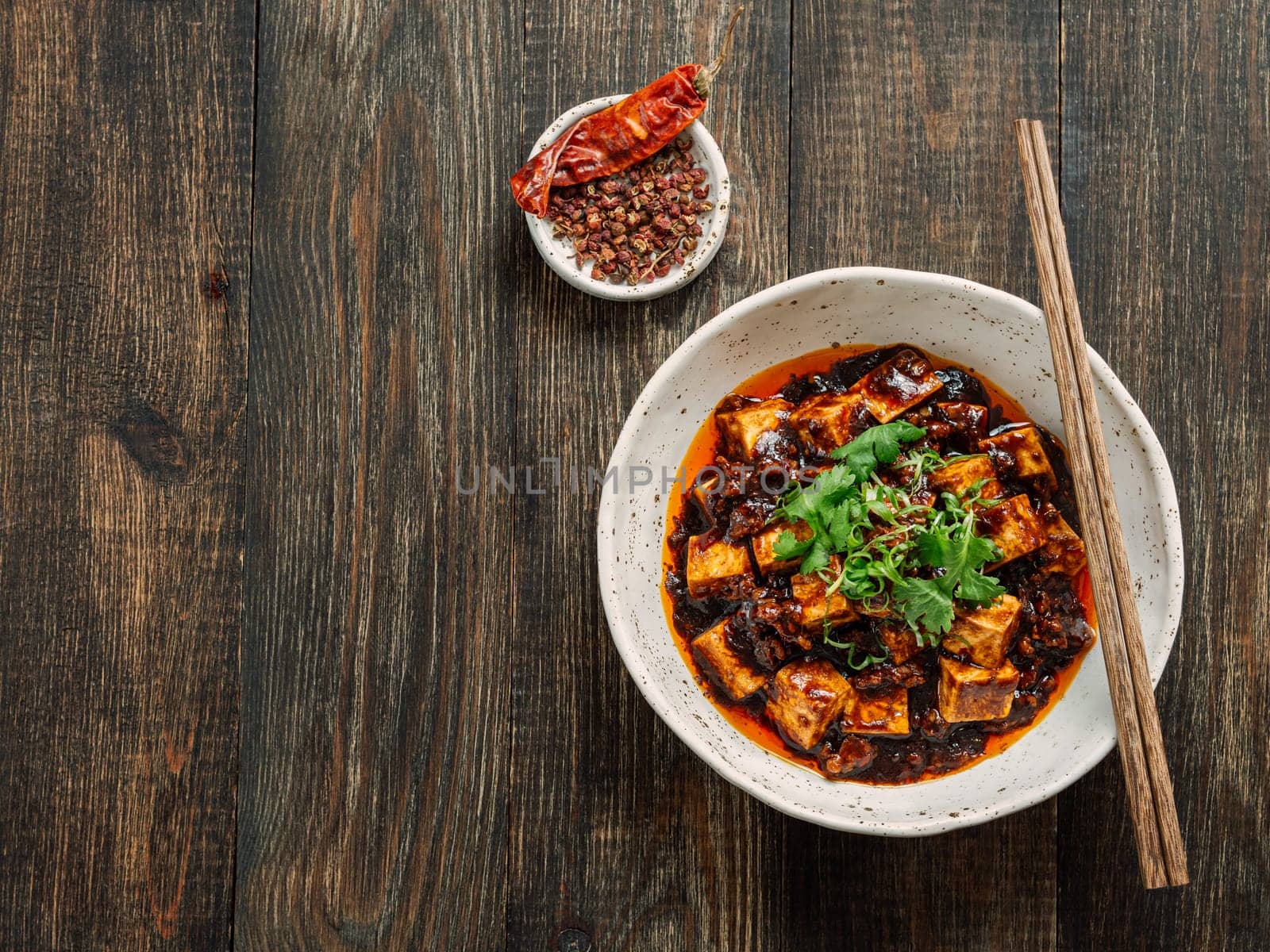 Spicy asian tofu salad or appetizer. Fried tofu decorated green onion - chinese dish with sauce. Serving Asian dish on brown wooden tabletop. Top view, copy space