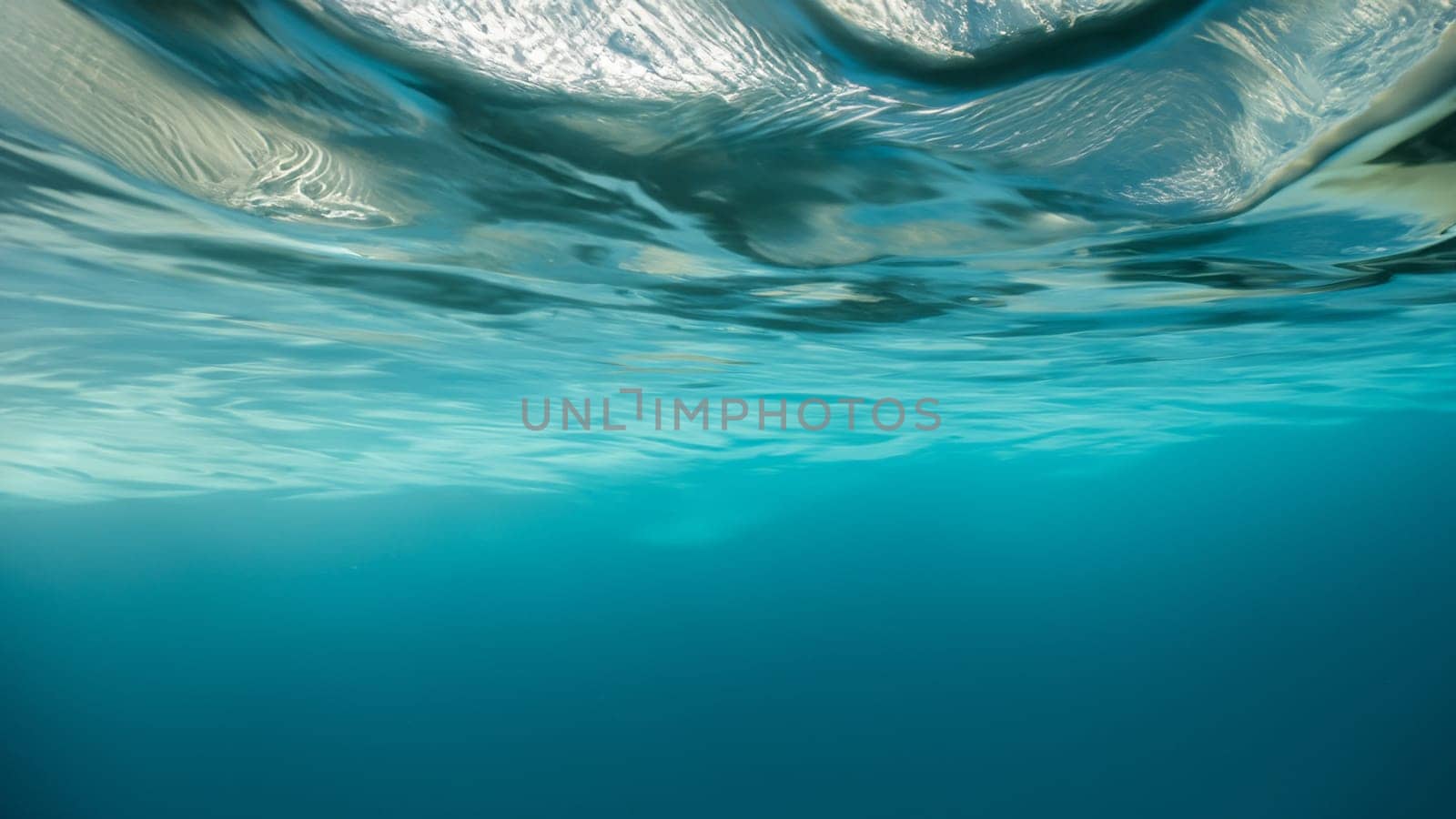 Underwater view of clear blue sea water surface with waves and bubbles, copy space