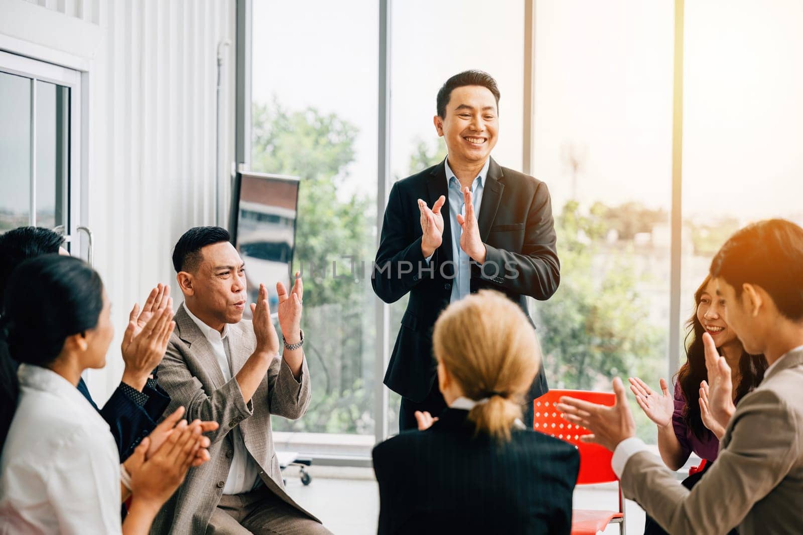 During a seminar, a teacher explains strategies, and the diverse audience raises hands to ask questions. This fosters cooperation, learning, and effective leadership.