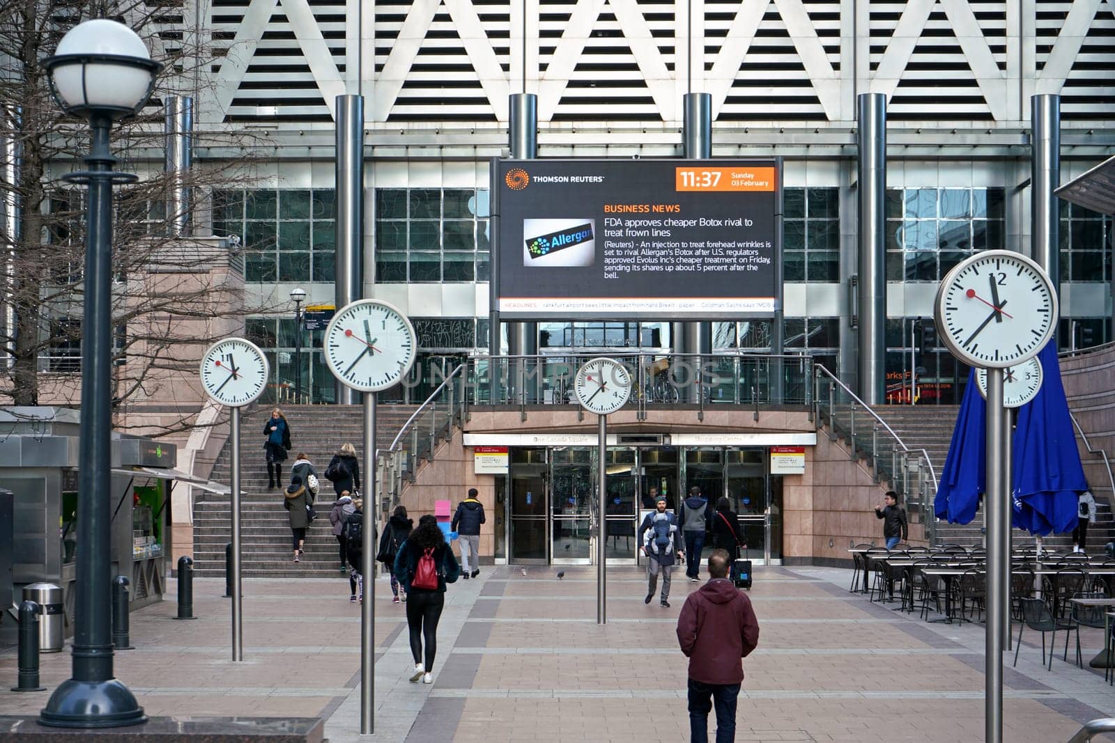 London, United Kingdom - February 03, 2019: People walk under Six Public Clocks - famous art design by Konstantin Grcic at Canary Wharf. Every of 12 clocks shows different numeral by Ivanko