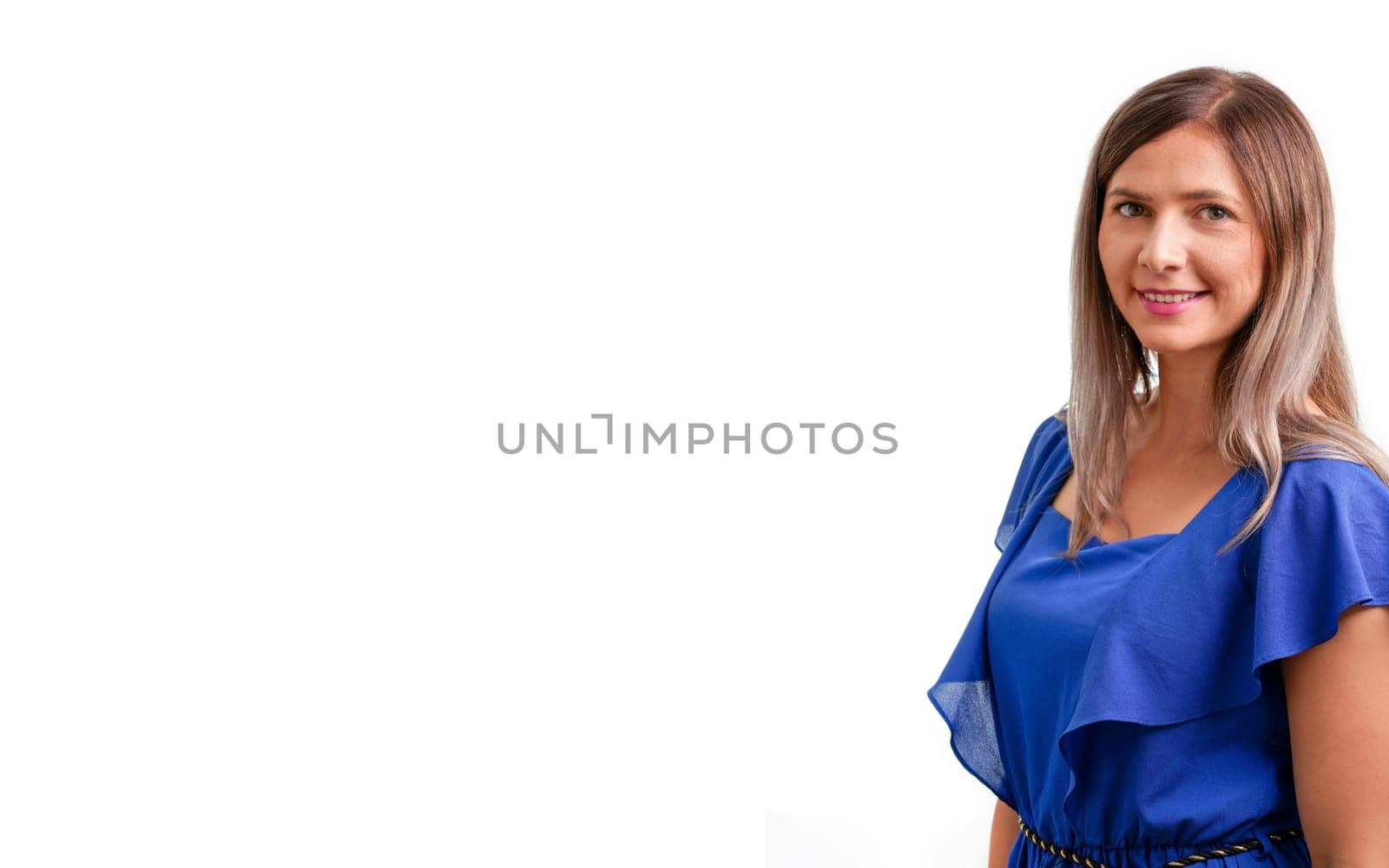 Young brunette woman in blue dress looking into camera, smiling, white background and space for text left side