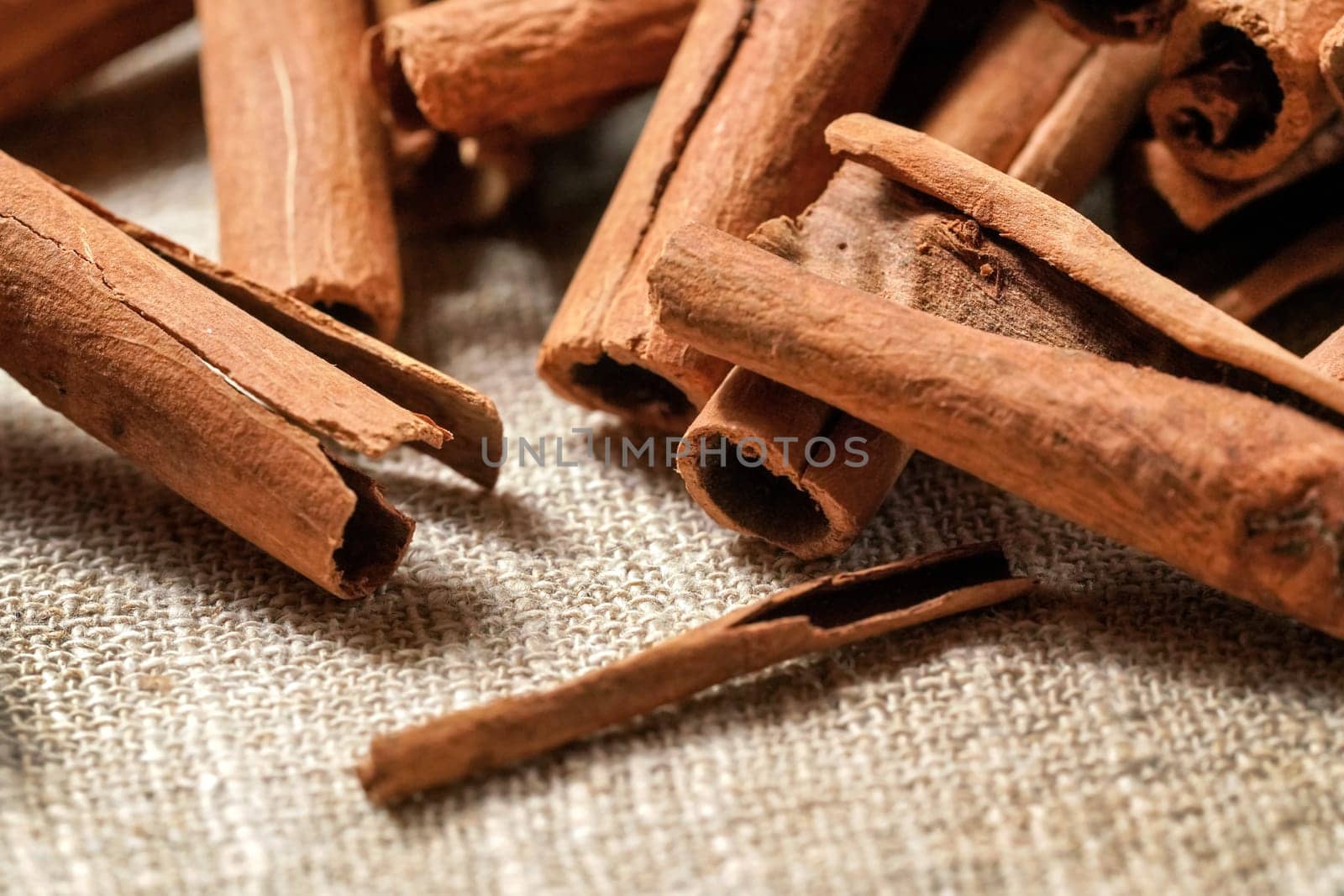 Closeup detail macro - Heap of cinnamon bark sticks on linen tablecloth. 