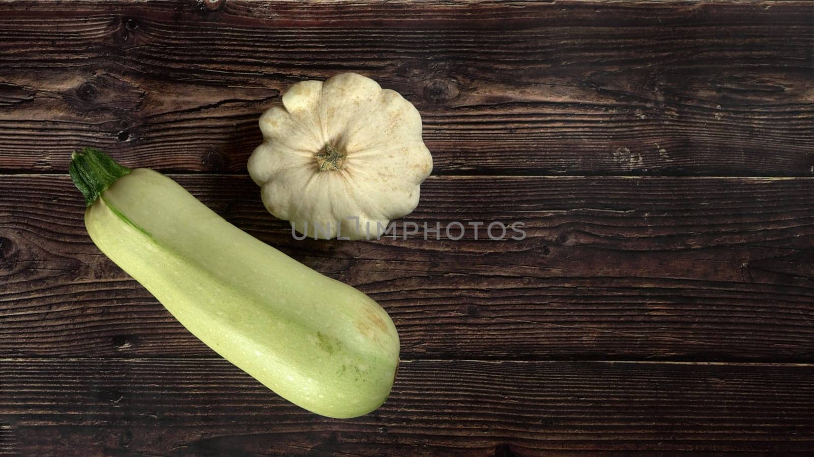 Top down view, pattypan squash and zucchini on dark wooden board, wide banner, space for text right side by Ivanko