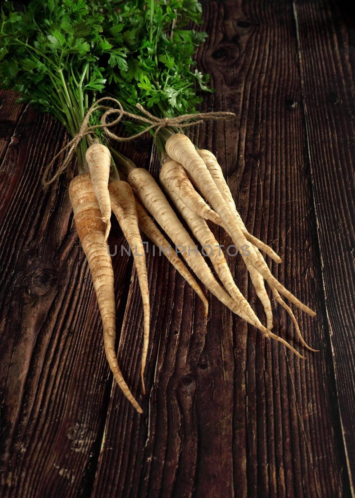 Bunch of parsley roots with green leaves on dark wooden board