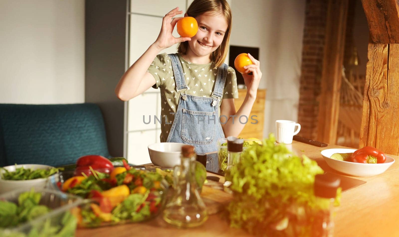 Girl child holding oranges at kitchen and smiling. Pretty female kid with citrus fruits and vegetables preparing vegetarian lunch