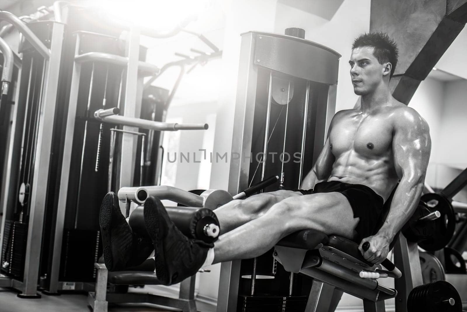 Strong muscular bodybuilder doing legs with machine by GekaSkr