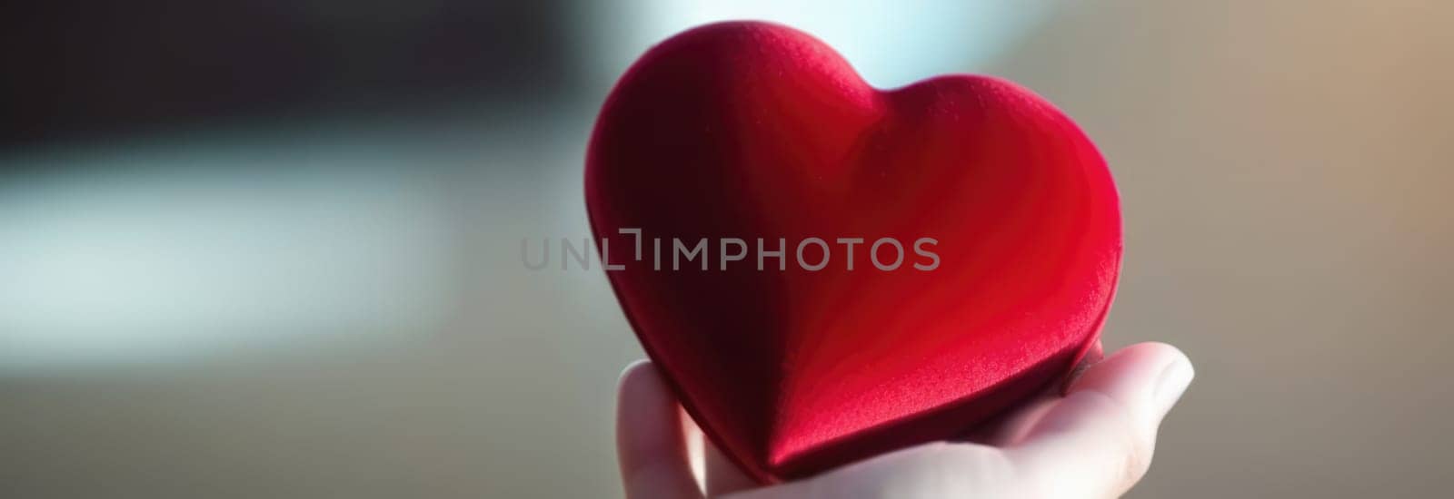 Beautiful fluffy voluminous red velvet heart lies on palm in closeup. Womans hand holds heart on blurred background. Copy space. For valentines, mothers day greeting card, love sale banner, voucher. by Angelsmoon