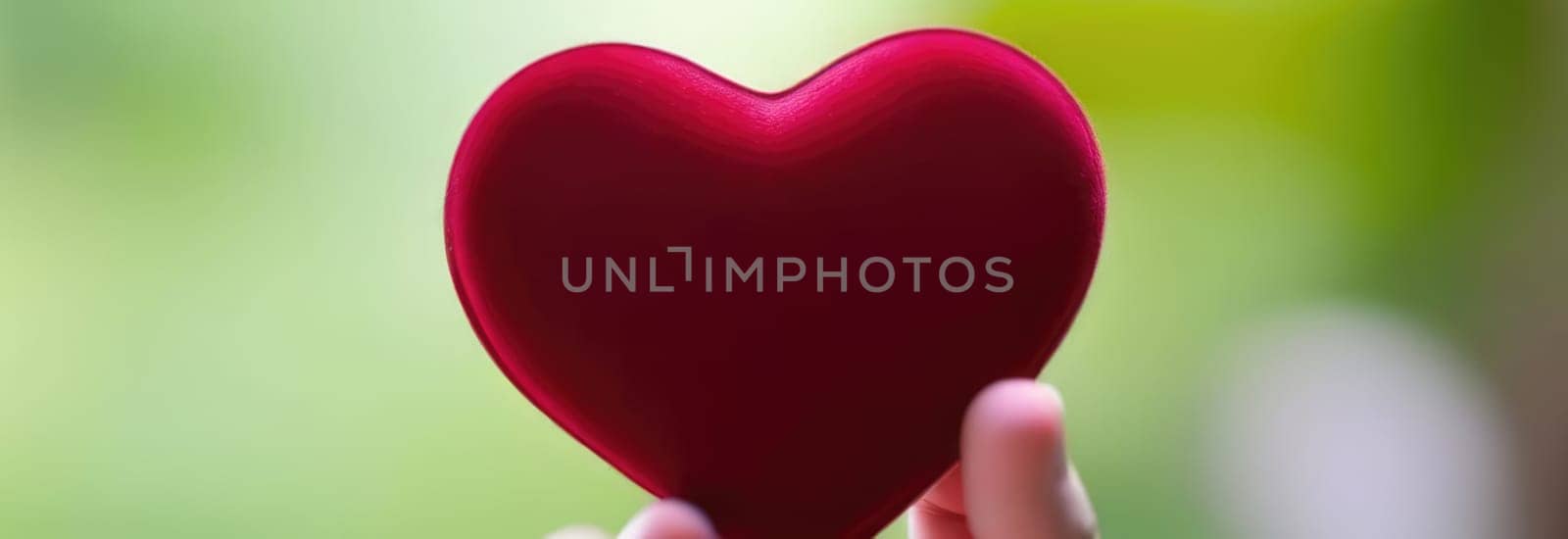 Beautiful fluffy voluminous red velvet heart lies on palm in closeup. Womans hand holds heart on blurred background. Copy space. For valentines, mothers day greeting card, love sale banner, voucher