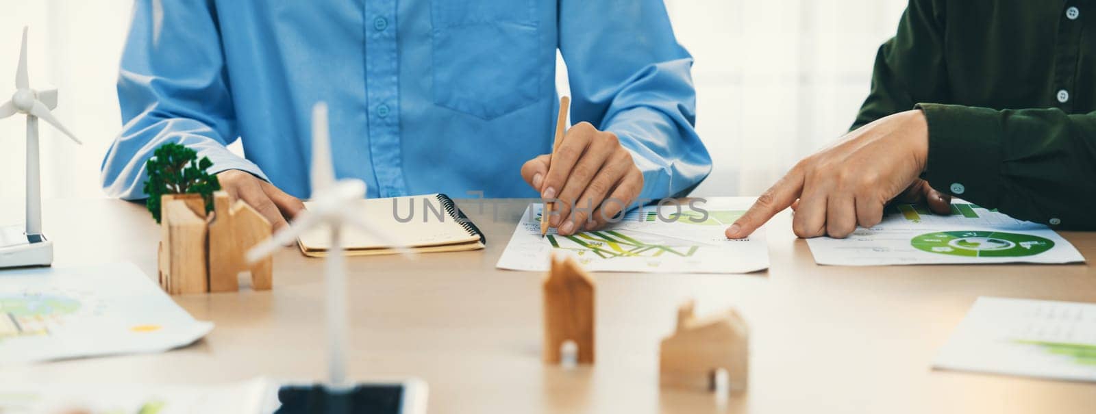 Business people invest in green business plan at meeting room on table with house model and wind mill placed represented eco house and renewable energy. Closeup. Delineation.