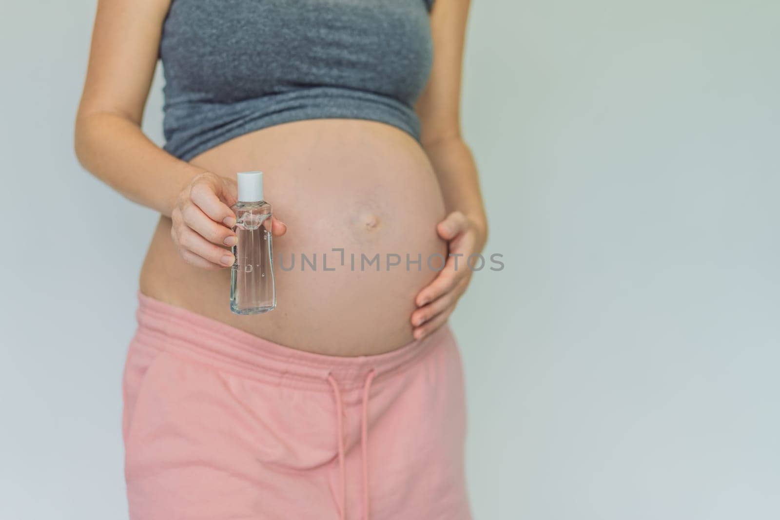 Expectant mom ensures safety, applying gel sanitizer for a clean and healthy pregnancy.